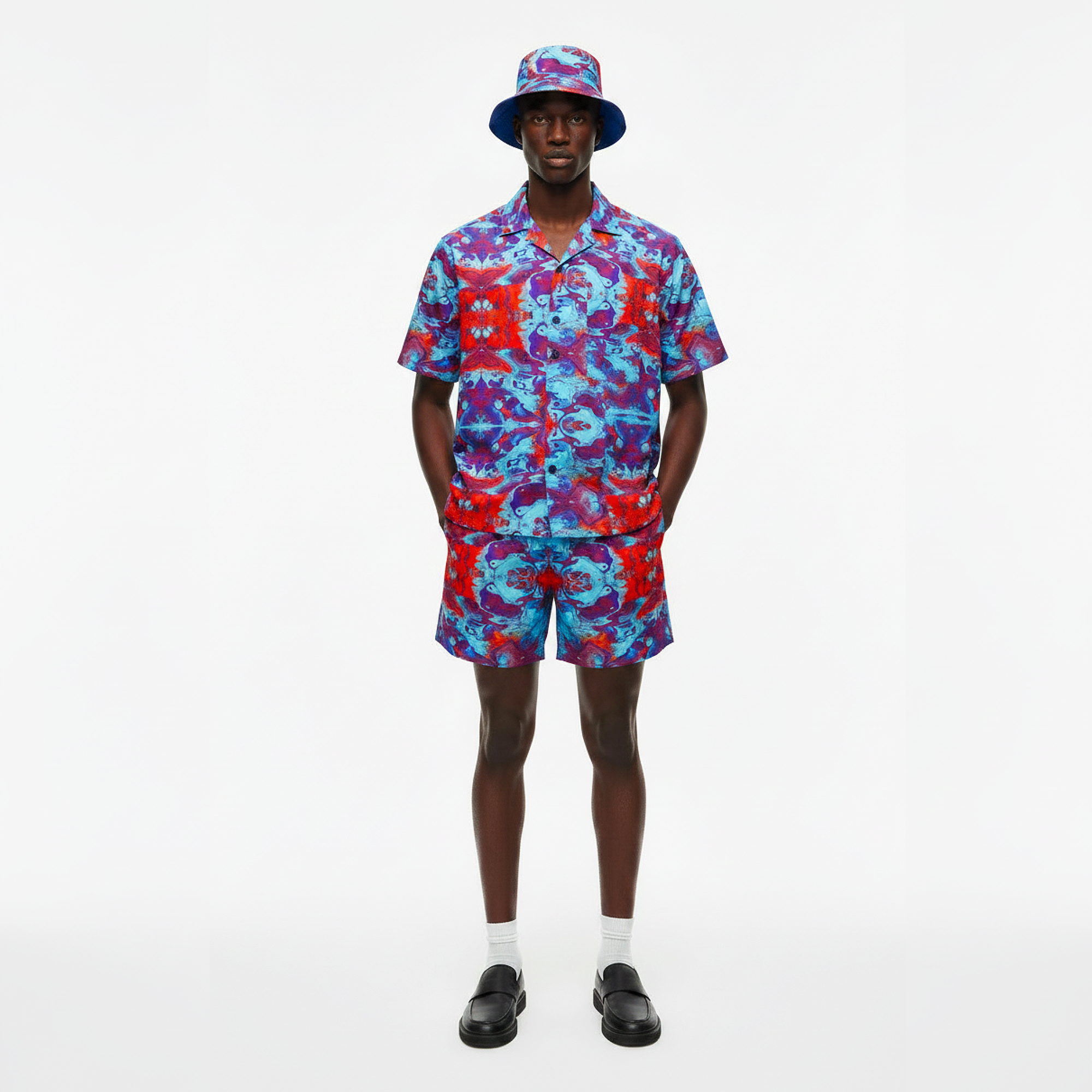 Person wearing a colorful shirt and shorts set with a matching hat on a white background