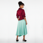 Woman wearing a dress with a red blouse and light green skirt on a white background