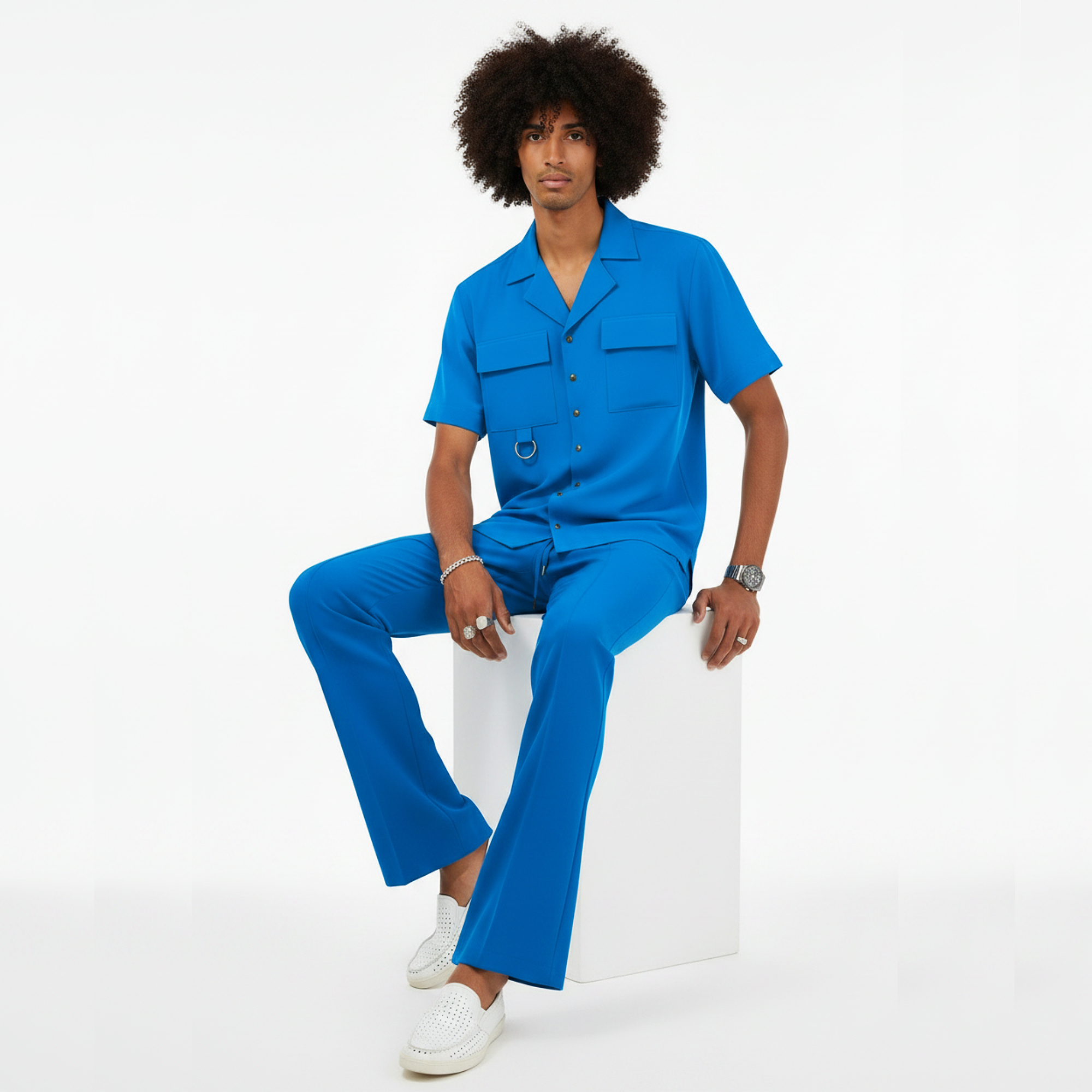 Person wearing a blue outfit sitting on a white stool against a white background