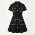 A black short-sleeve shirt dress with white contrast stitching, button details, and flap pockets, shown against a light gray background.