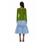 Woman wearing a dress with a green top and blue skirt on a white background