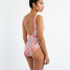 Woman wearing a pink floral one-piece swimsuit on a white background