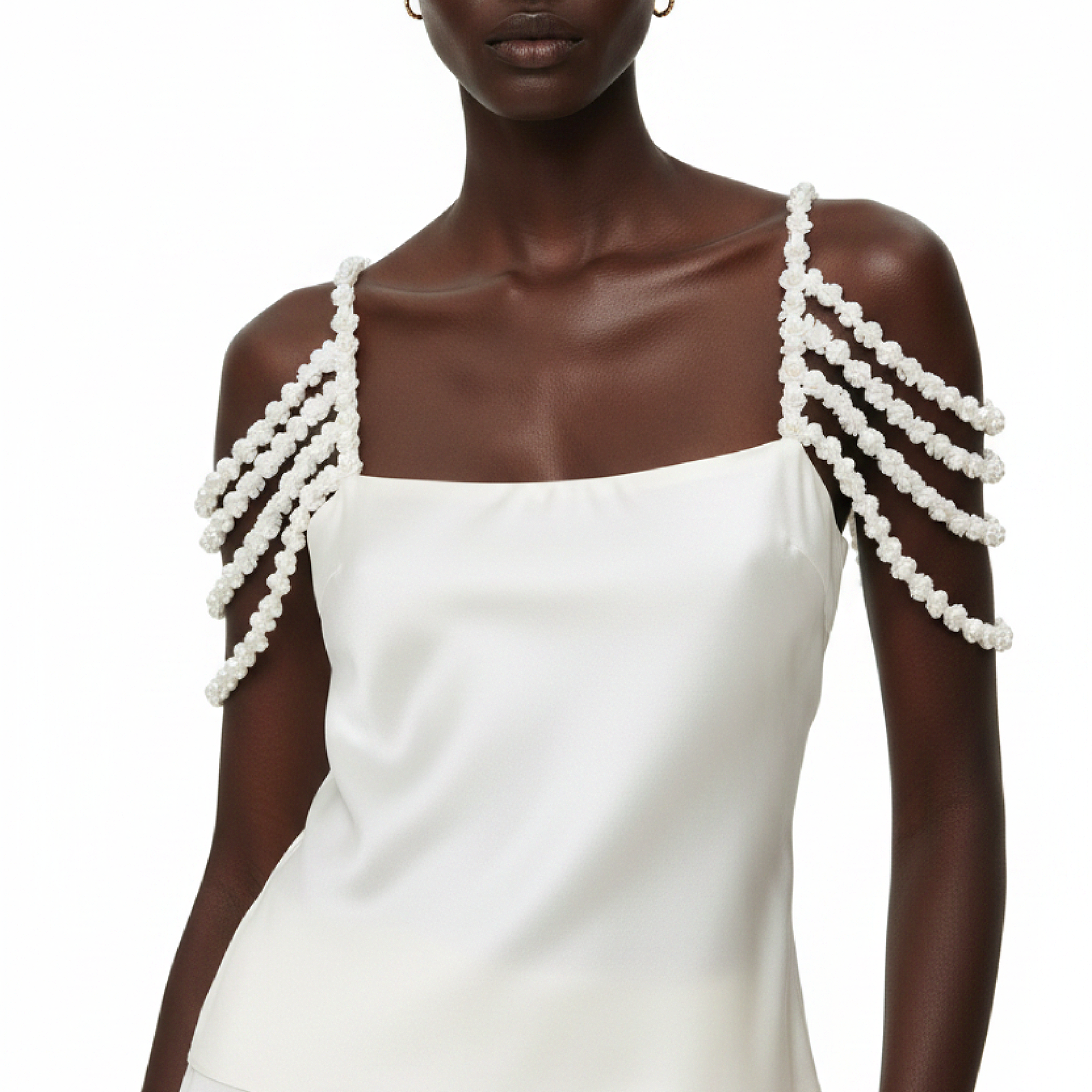 A person wearing a white top with pearl shoulder straps on a white background