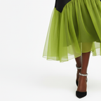 Green sheer skirt with black top and shoes on a white background