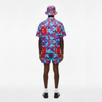 Person wearing a colorful shirt, shorts, and bucket hat on a white background