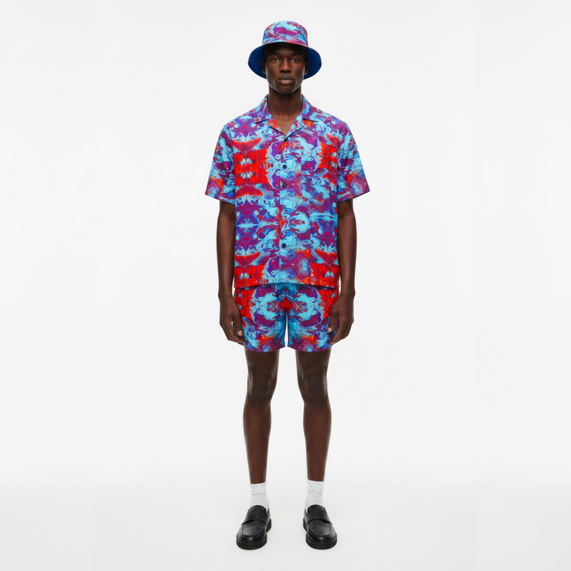 Person wearing a colorful patterned outfit with a hat on a white background