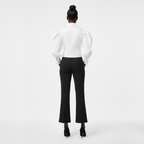Person wearing a white blouse and black pants on a white background