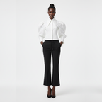 Person wearing a white blouse and black pants on a white background