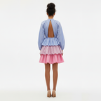 Woman wearing a blue and pink dress with an open back on a white background