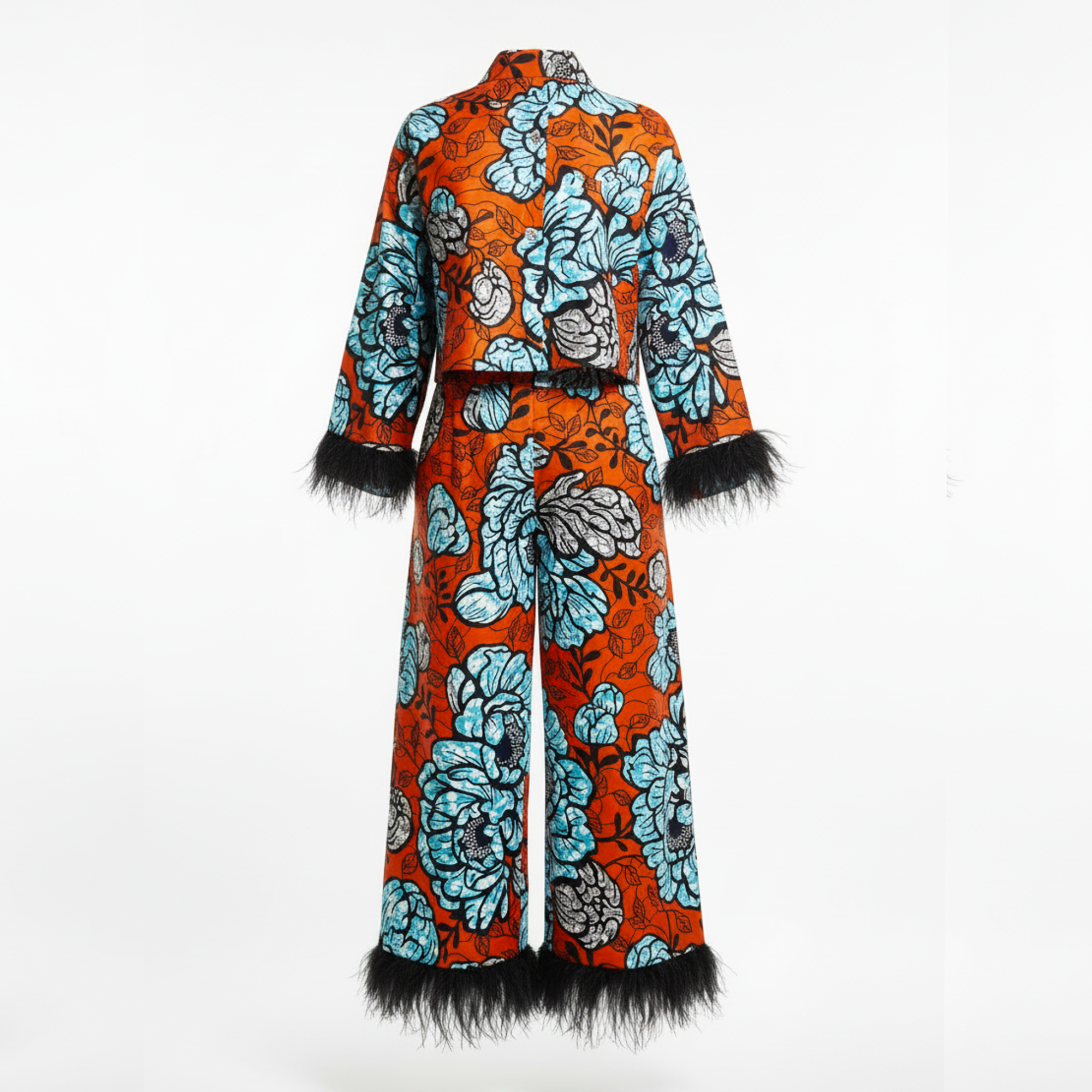 A two-piece matching set consisting of a long-sleeve cropped jacket and wide-leg trousers, featuring a vibrant orange base with a large light blue and gray floral print, finished with black feather trim at the cuffs and hem.