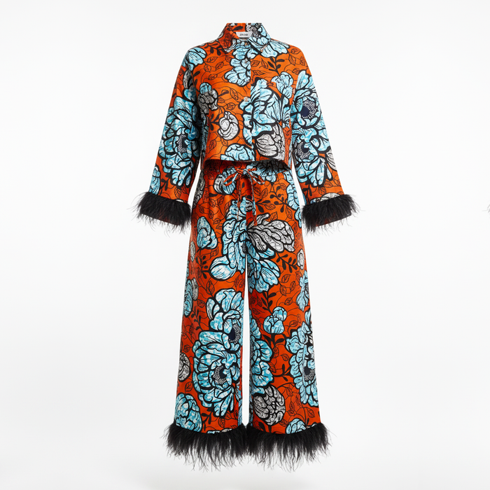 A long-sleeve, high-neck two-piece outfit with a bold orange, light blue, and black floral print, finished with black feather trim at the cuffs and hem, shown against a plain white background.