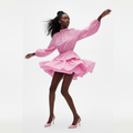 Woman wearing a pink dress with long sleeves and a flared skirt on a white background