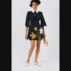 Woman wearing a black dress with floral designs on a white background