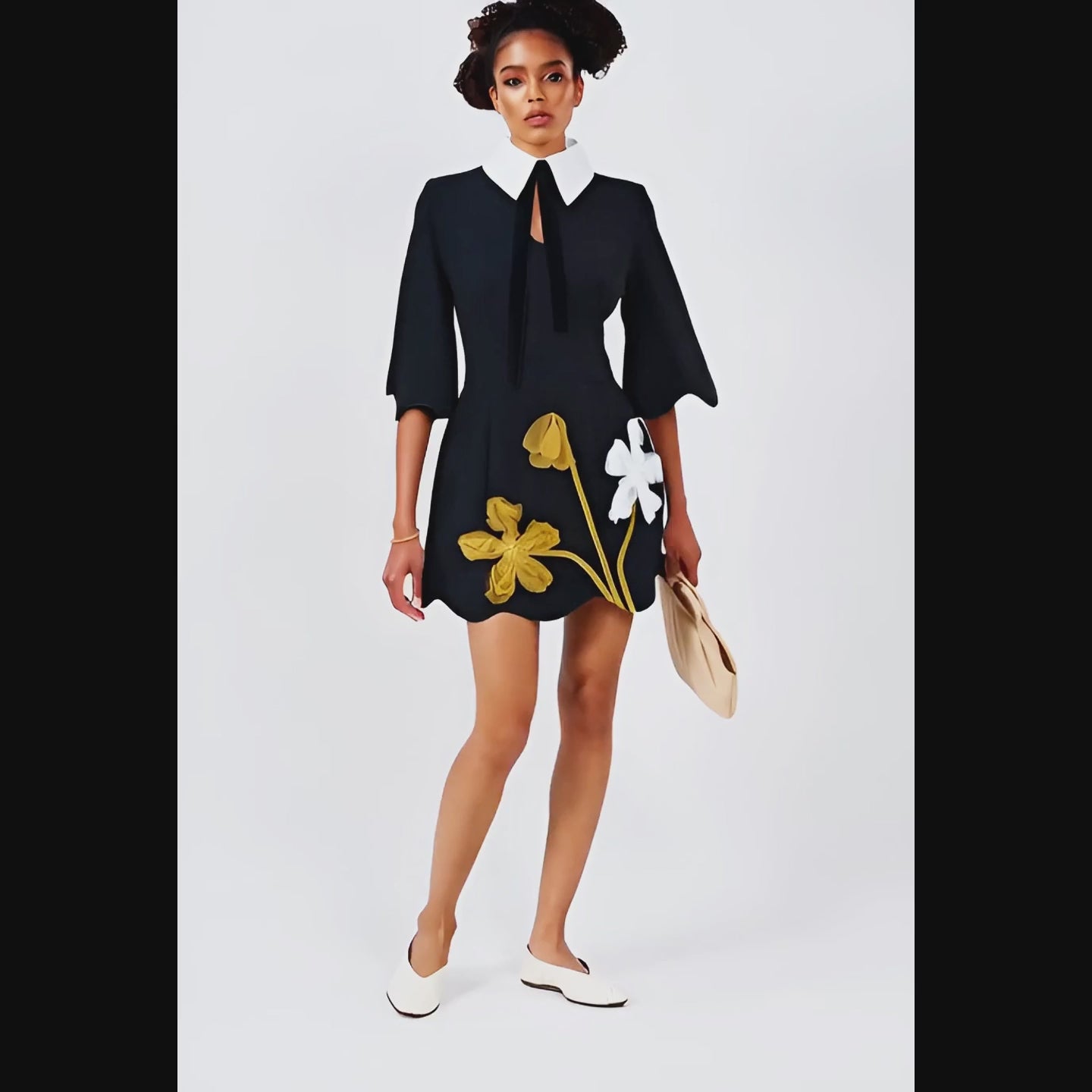 Woman wearing a black dress with floral designs on a white background
