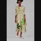 Woman wearing a beige dress with green clover patterns on a white background