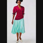 Woman wearing a dress with a red top and light blue skirt on a white background