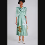 Woman wearing a green dress with floral designs against a white background