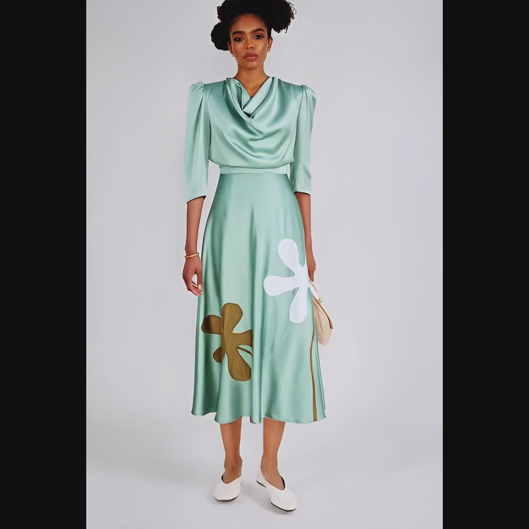 Woman wearing a green dress with floral designs against a white background