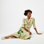 Woman wearing a beige dress with green clover patterns on a white background