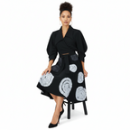 Woman wearing a black coat with white patterned skirt on a white background