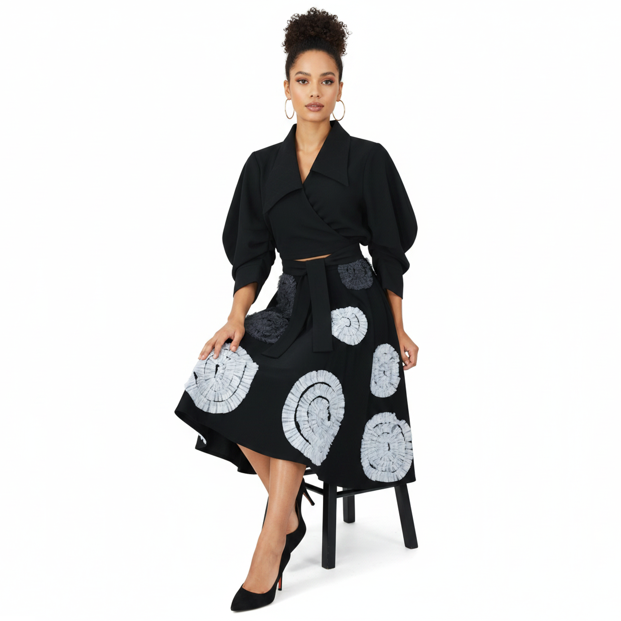 Woman wearing a black coat with white patterned skirt on a white background