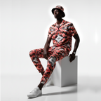 Man wearing a colorful floral outfit sitting on a white block against a light gray background