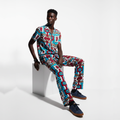 Person wearing a colorful patterned outfit sitting on a white block against a white background