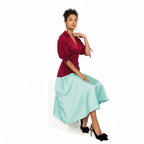 Woman wearing a dress with a red top and light blue skirt on a white background