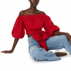 Woman wearing a red off-shoulder top with a blue jeans on a white background
