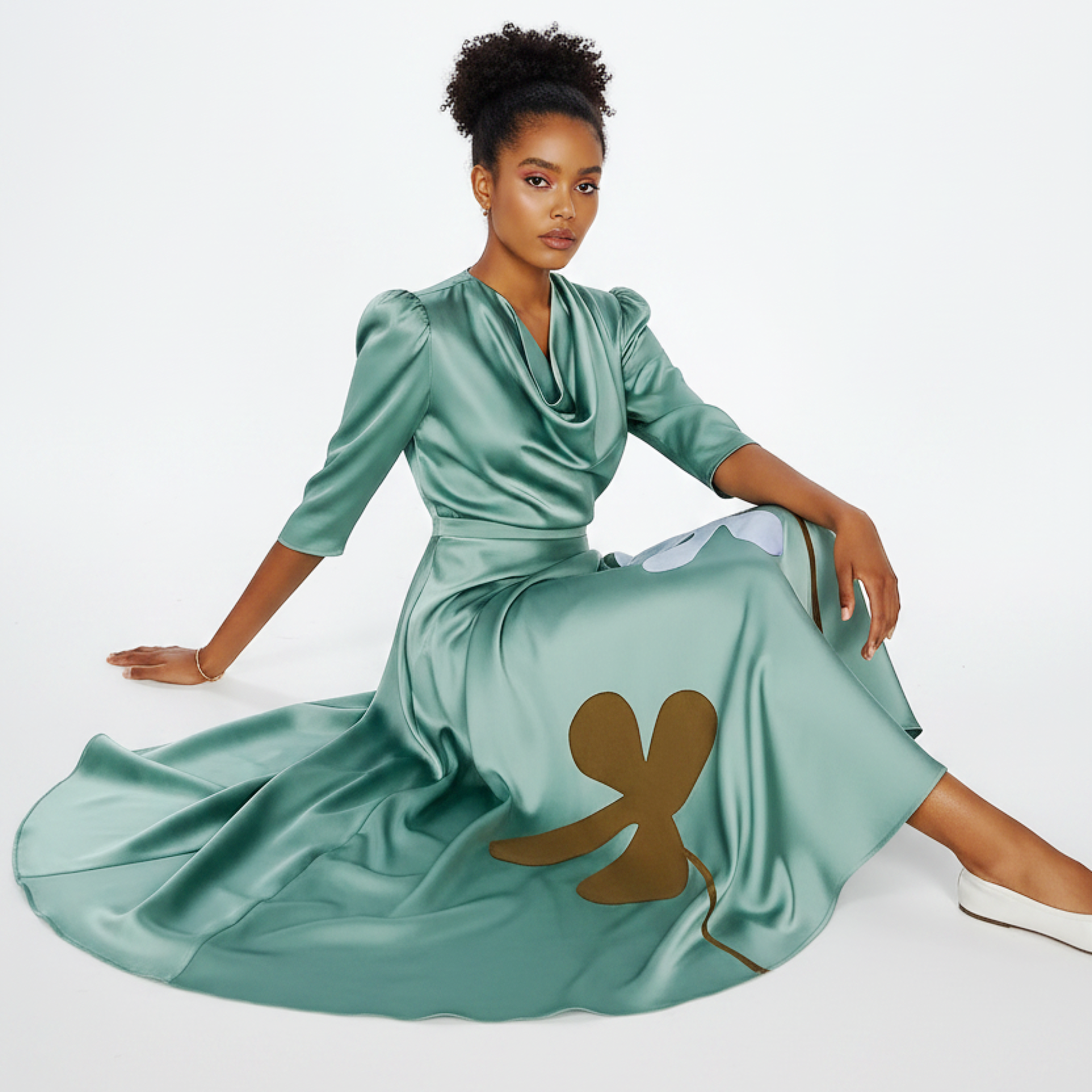 Woman wearing a green dress with floral designs against a white background