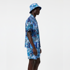 Person wearing a blue patterned shirt and bucket hat on a white background