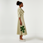 Woman wearing a beige dress with green clover patterns on a white background