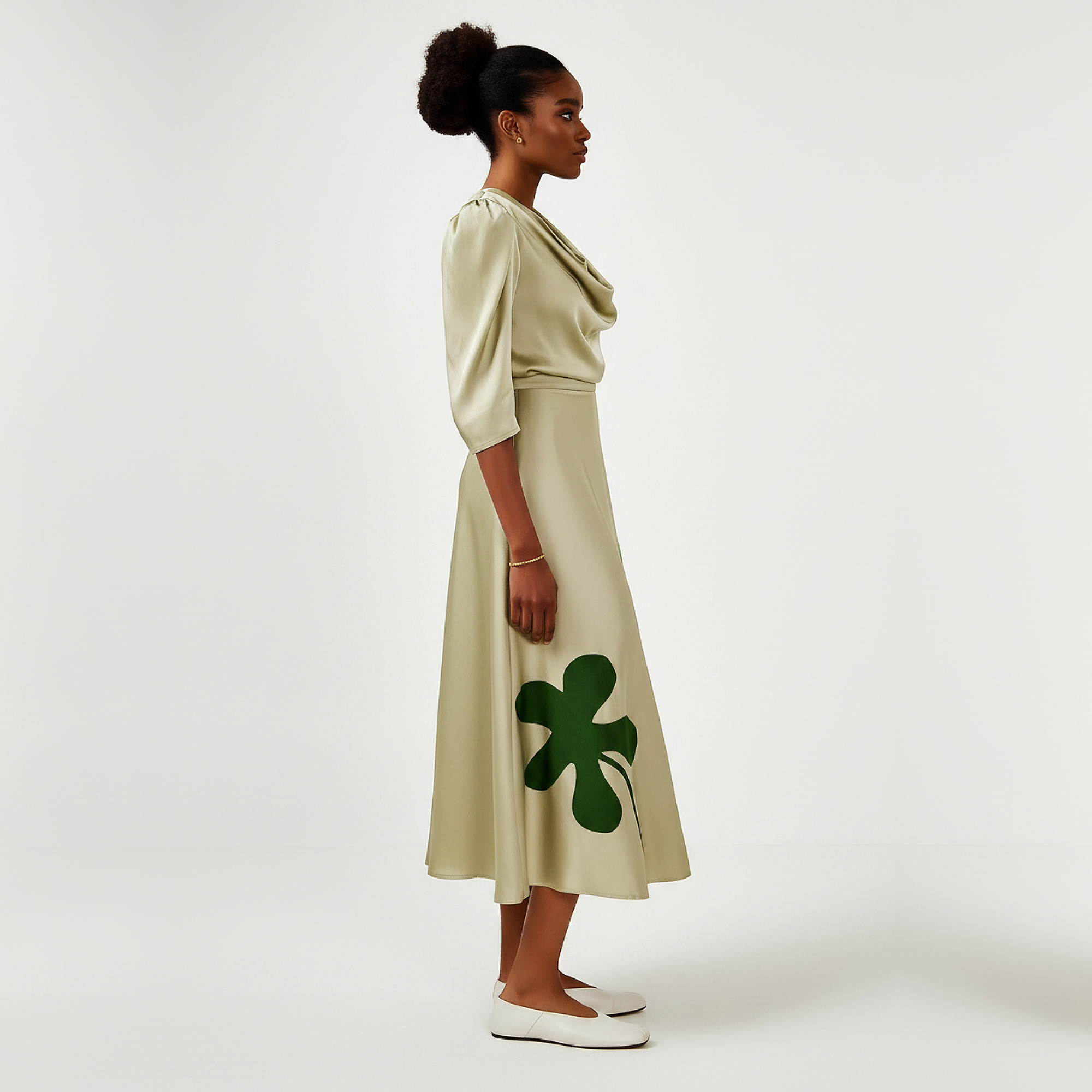 Woman wearing a beige dress with green clover patterns on a white background