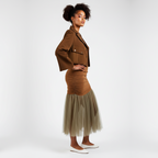 Woman wearing a brown jacket and skirt with a beige tulle hem on a white background
