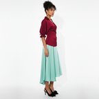 Woman wearing a dress with a red top and light green skirt on a white background