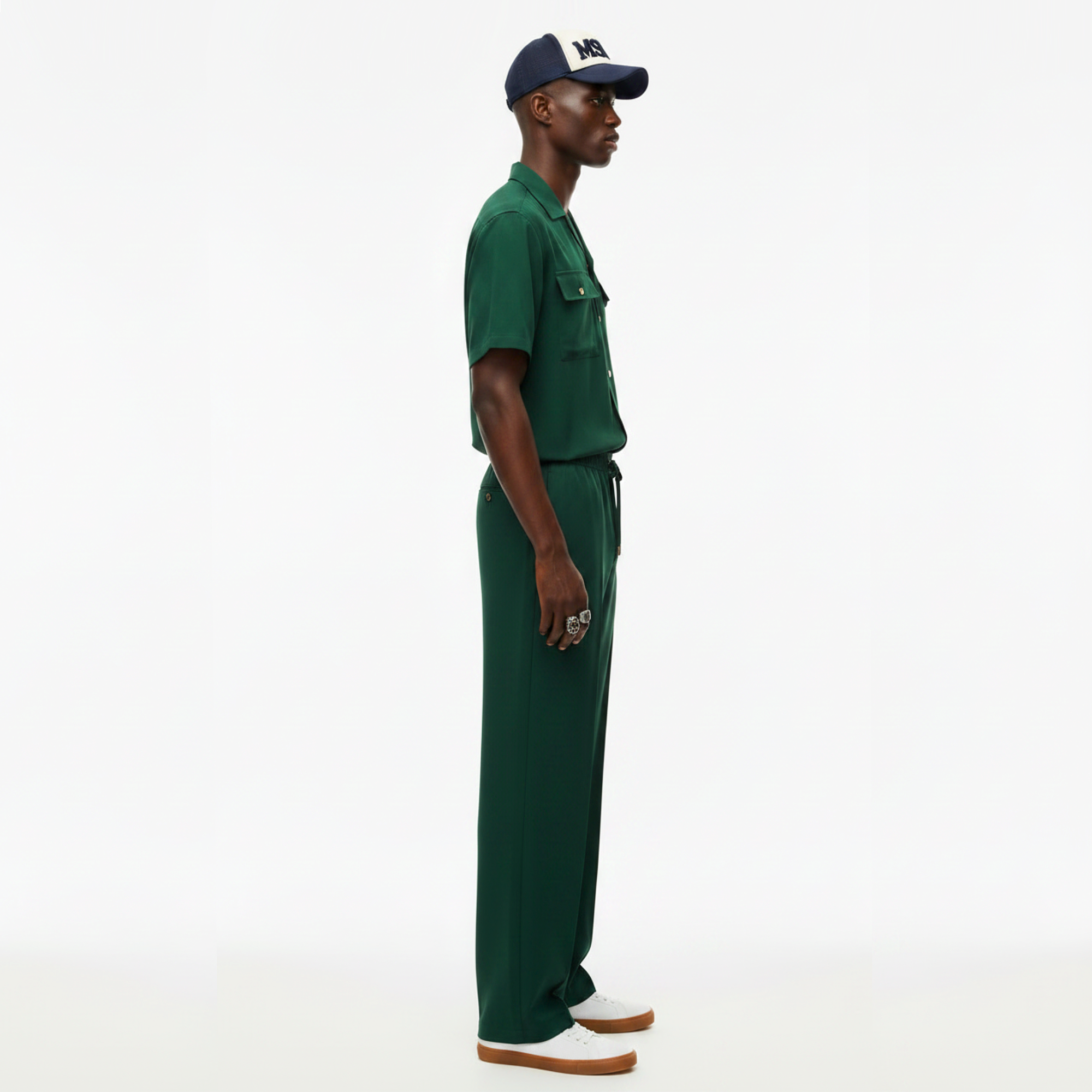 Man wearing a green outfit with a cap on a white background