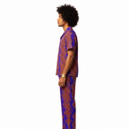 Man wearing a patterned shirt and pants on a white background