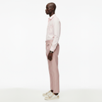 Man wearing a light pink shirt and matching pants on a white background
