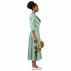 Woman wearing a green dress with floral designs against a white background