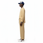 Man wearing a beige outfit with a navy cap on a white background