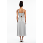 Woman wearing a light white dress with cut-out back design on a white background