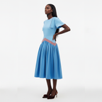 Woman wearing a light blue dress with a pink belt on a white background