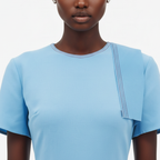 Person wearing a light blue top with a plain background