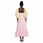 Woman wearing a pink dress with yellow sleeves on a white background