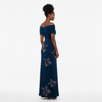 Woman wearing a blue off-shoulder gown with floral details on a white background
