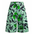 Green and black tropical print wide-leg shorts featuring hibiscus flowers and leaves over a white background with a green scribble pattern.